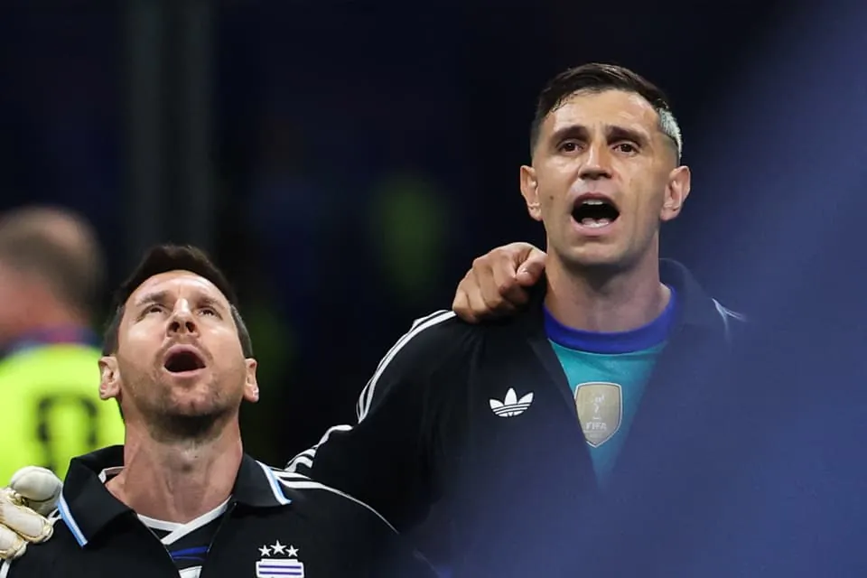 Argentina s forward 10 Lionel Messi L and goalkeeper 23 Emiliano Martinez R sing their national anthem ahead of the 2026 World Cup football tournament semi final match between England and Arg
